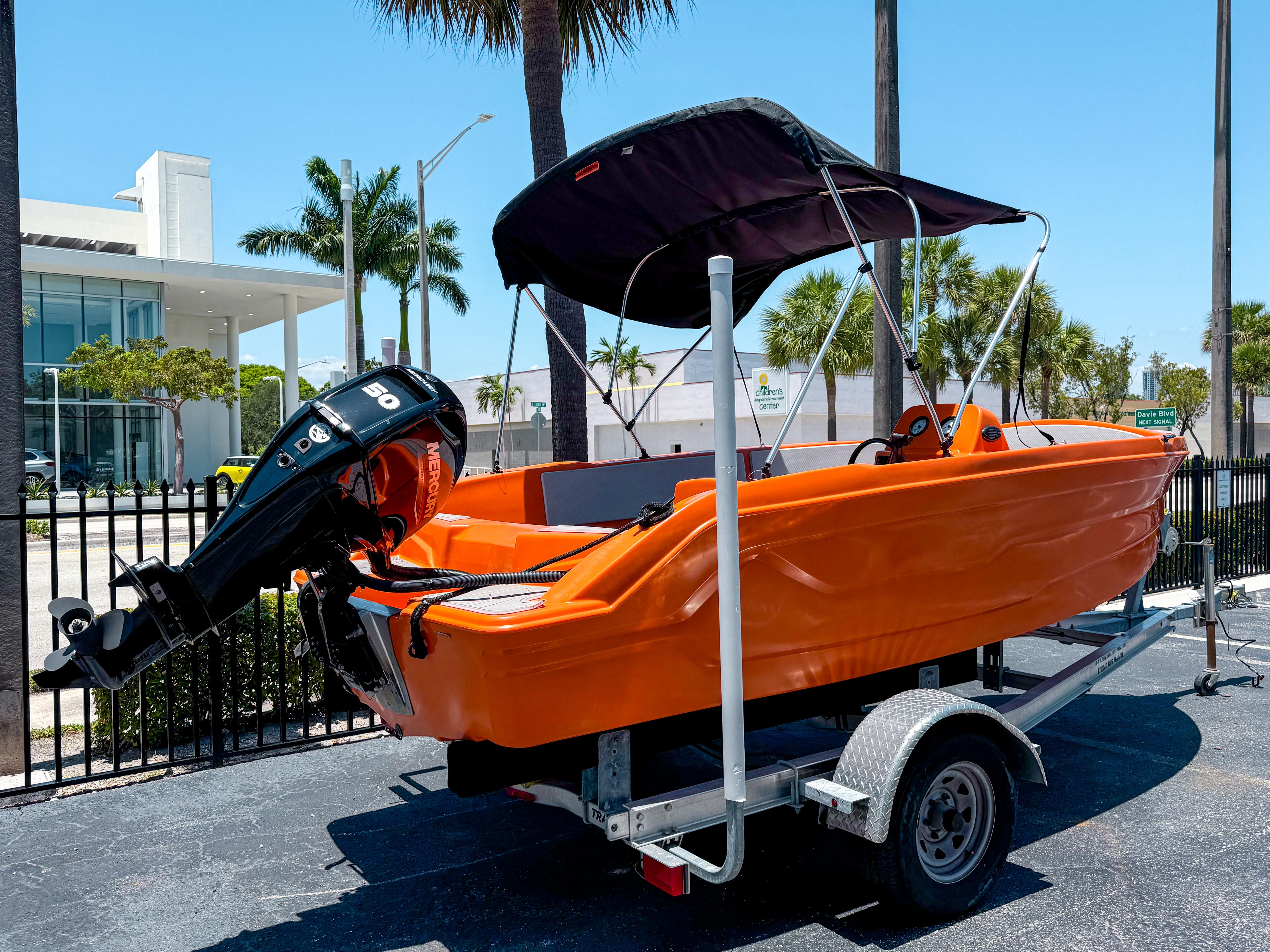 2024 Vision Marine Technologies Phantom boat, orange, on trailer, with canopy, parked outdoors.