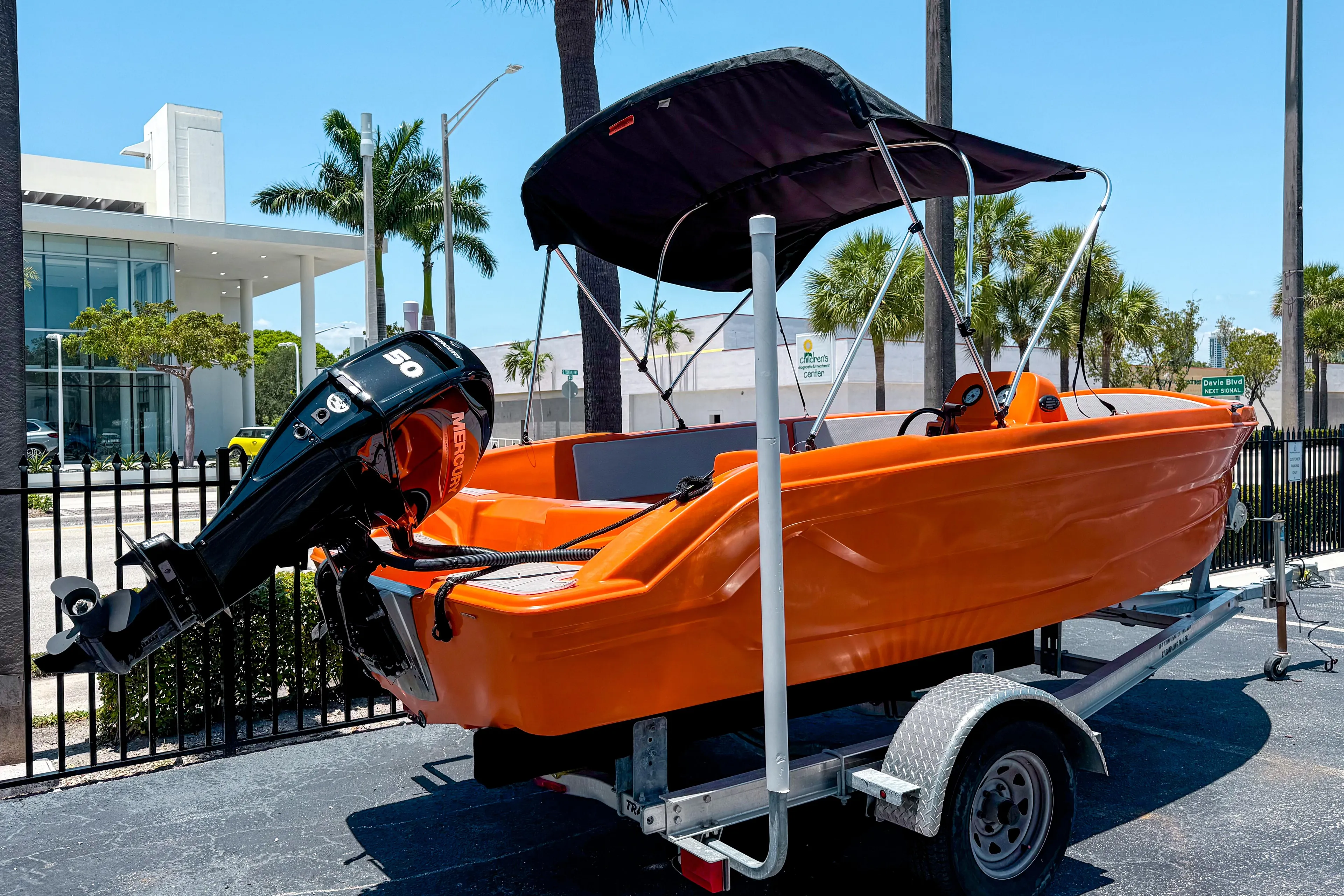 2024 Vision Marine Technologies Phantom boat, orange, on trailer, with canopy, parked outdoors.