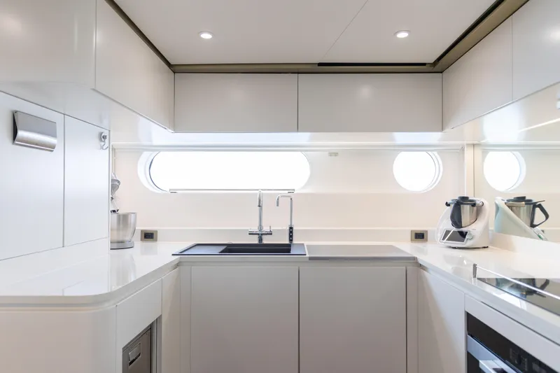 Palmax Yacht Photos Pics Modern kitchen interior on 2022 Azimut Magellano 30M yacht, featuring sleek white cabinetry and appliances.