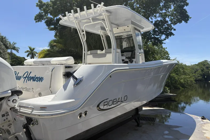 302-112 Yacht Photos Pics 2023 Robalo R302 Center Console boat docked near lush greenery.