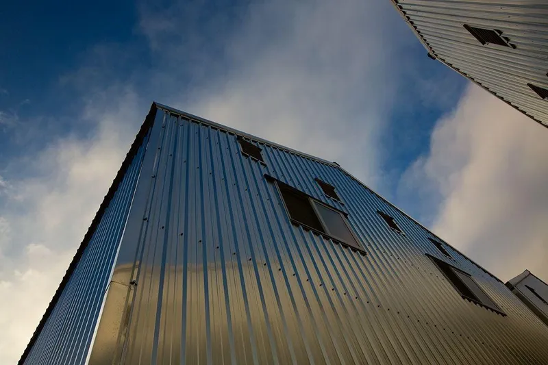  Yacht Photos Pics Modern Custom OBMG Boathouse 2025 with metal siding against a cloudy blue sky.