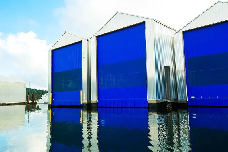  Yacht Photos Pics Modern 2025 Custom OBMG Boathouse with blue doors reflecting on water.