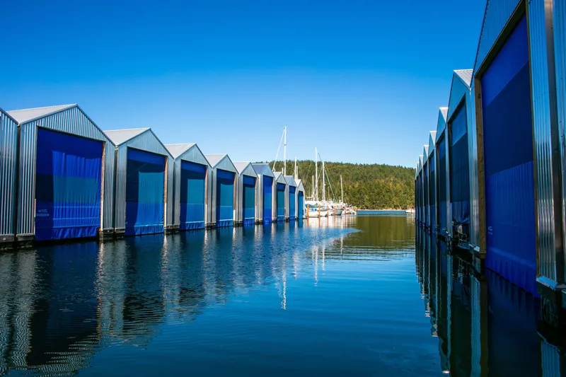  Yacht Photos Pics Modern boathouses with blue doors reflecting on calm water, Custom OBMG Boathouse 2025.