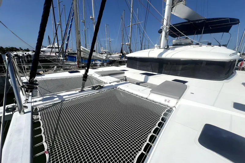 Capricho Yacht Photos Pics 2011 Lagoon 560 catamaran docked, featuring spacious deck and netting under clear blue sky.
