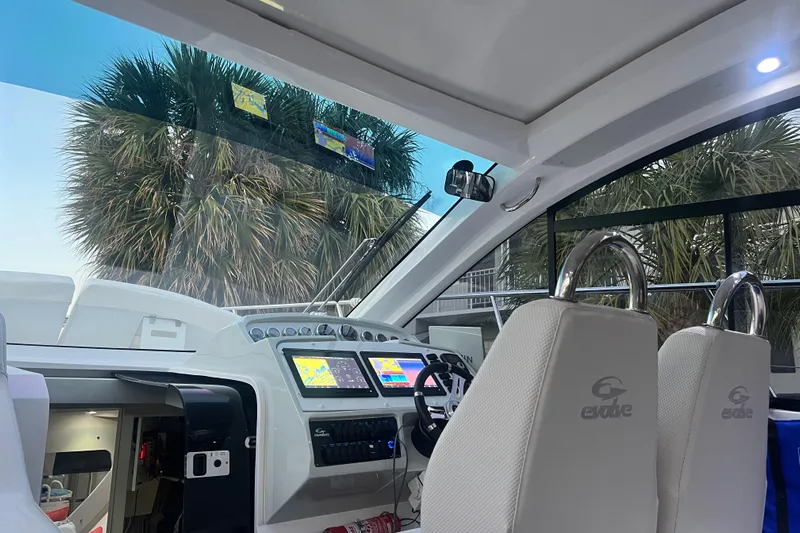 Romaniac Yacht Photos Pics Interior of 2021 Evolve 400HT boat with modern dashboard and palm trees outside.