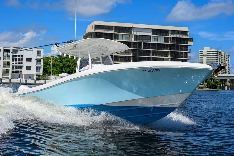  Yacht Photos Pics 2023 Powerplay Powerboats 30 RumRunner cruising on water near modern buildings.