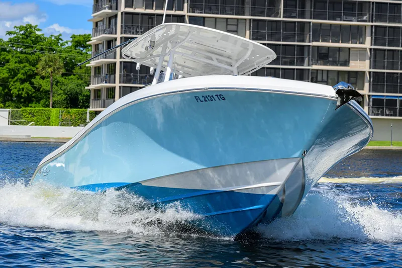  Yacht Photos Pics 2023 Powerplay Powerboats 30 RumRunner cruising on water near modern buildings.