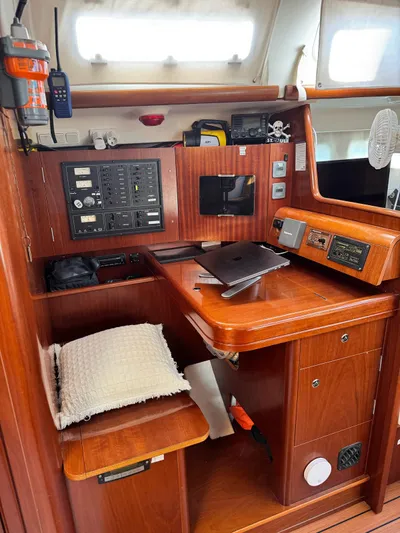  Yacht Photos Pics Navigation station inside 2006 Beneteau Oceanis 473 sailboat with control panels and wooden finish.