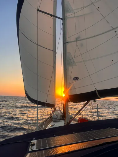  Yacht Photos Pics Beneteau Oceanis 473 sailing at sunset, 2006 model, with full sails on open water.