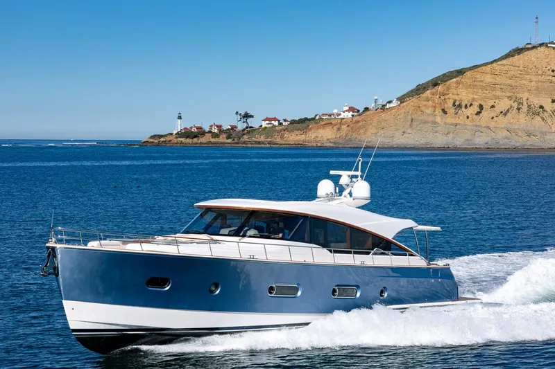 Valencia Yacht Photos Pics 2019 Belize 66 Sedan yacht cruising near a scenic coastal lighthouse.