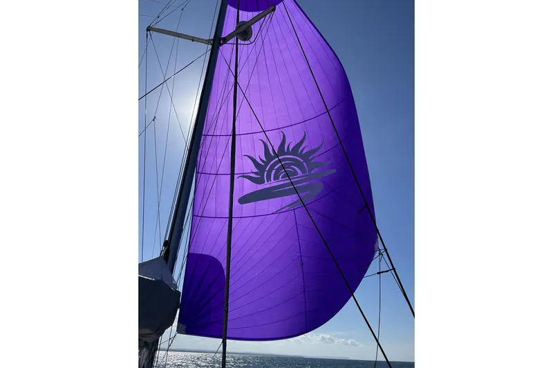Gtfo Yacht Photos Pics Purple sail with sun design on Balance 482 yacht, 2023 model, against clear blue sky.