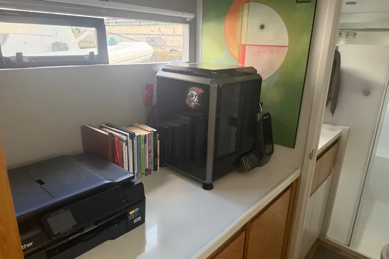 Gtfo Yacht Photos Pics Modern office setup with printer, books, and a 3D printer on a countertop.