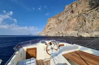 Trader 535 Signature 2001 yacht cruising near rocky coastline under clear blue sky.