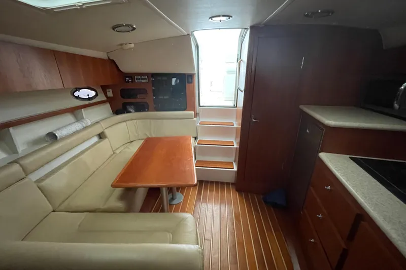  Yacht Photos Pics 2003 Tiara Yachts 3100 Open interior with beige seating, wooden table, and kitchenette.