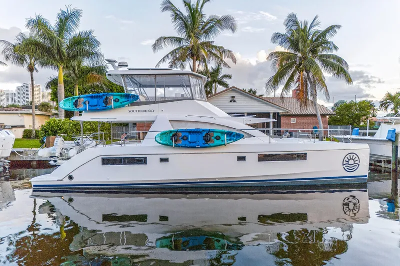 Southern Sky Yacht Photos Pics 2018 Leopard 51 Powercat yacht docked, featuring kayaks, palm trees, and a serene waterfront setting.