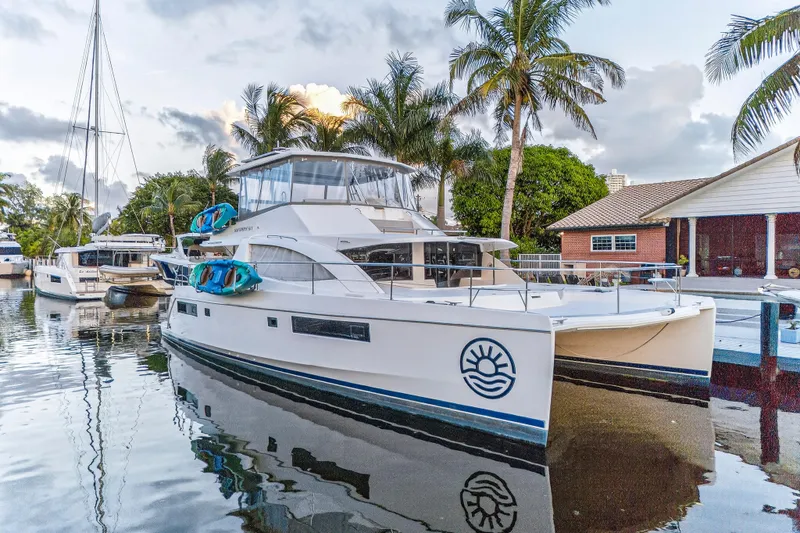 Southern Sky Yacht Photos Pics 2018 Leopard 51 Powercat yacht docked by palm trees and waterfront homes.