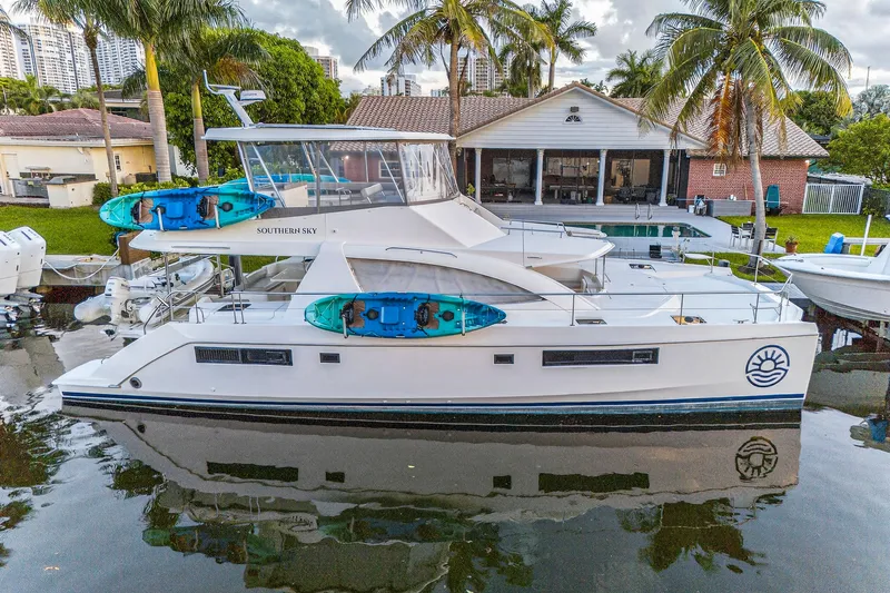 Southern Sky Yacht Photos Pics 2018 Leopard 51 Powercat docked with kayaks, surrounded by palm trees and waterfront homes.