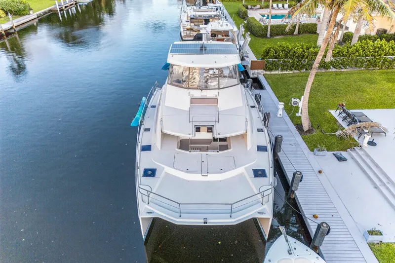 Southern Sky Yacht Photos Pics 2018 Leopard 51 Powercat docked by a waterfront property with lush greenery.