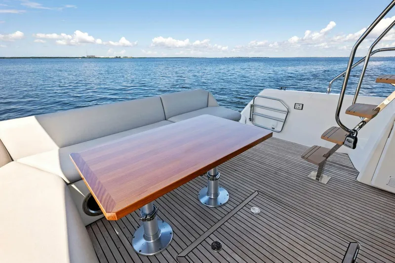 Jilligans Island Yacht Photos Pics Prestige 460 Flybridge 2023 yacht deck with wooden table and ocean view.