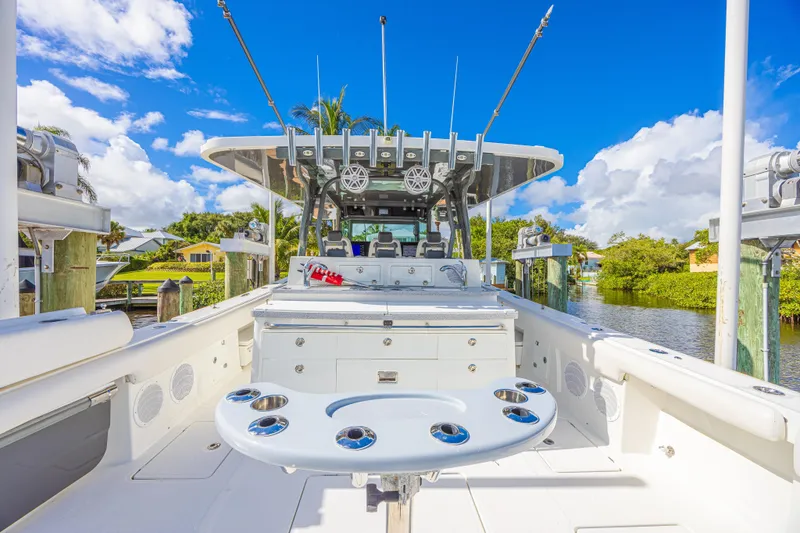 2022 425 Yamahas Yacht Photos Pics 2019 HCB 53 Sue&ntilde;os boat interior with fishing rod holders, docked by lush greenery.