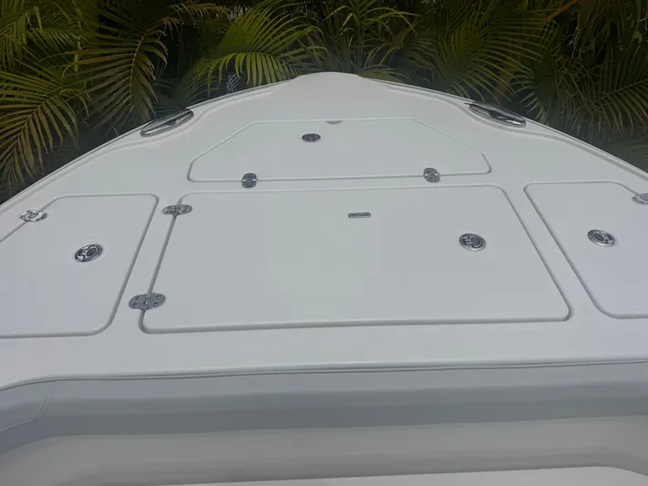  Yacht Photos Pics 2026 Blackfin 262 HB boat deck with storage hatches, surrounded by lush greenery.