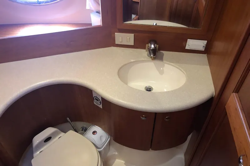Joie De Vivre Yacht Photos Pics 2003 Silverton 35 Motor Yacht bathroom with sink, toilet, and wooden cabinetry.