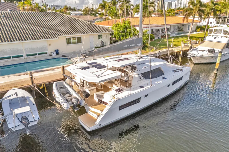  Yacht Photos Pics 2020 Leopard 45 catamaran docked by waterfront homes, featuring modern design and spacious deck.