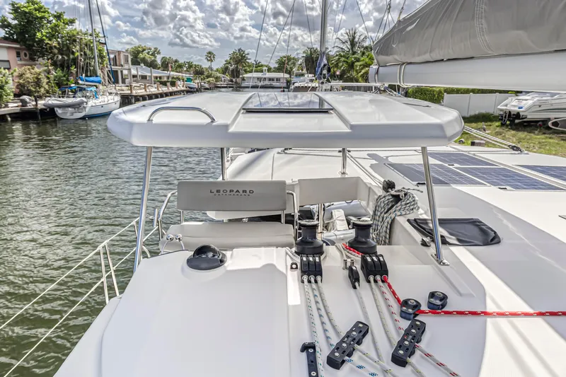  Yacht Photos Pics 2020 Leopard 45 catamaran on a sunny day, docked by a canal with lush surroundings.