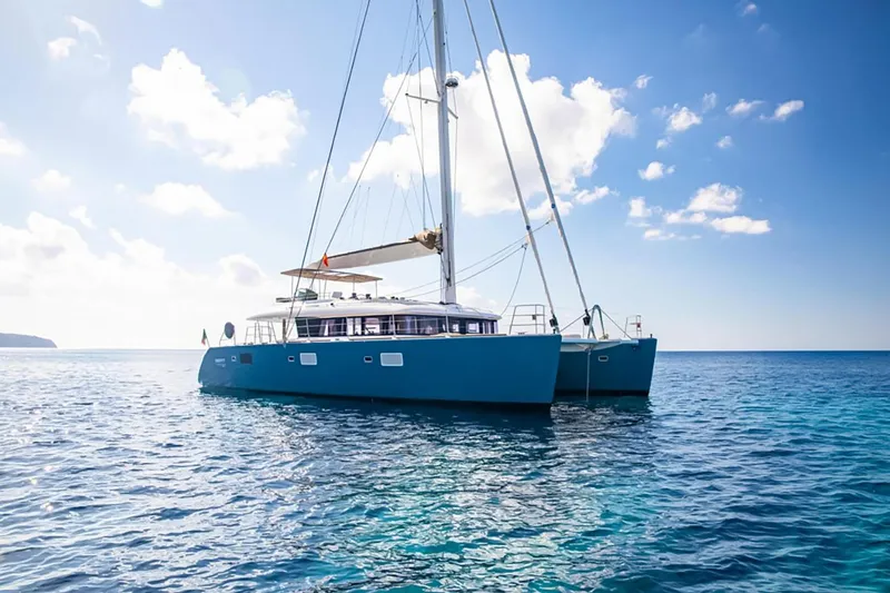 Firefly Yacht Photos Pics Luxurious 2012 Lagoon 620 NEO catamaran sailing on clear blue ocean under sunny skies.