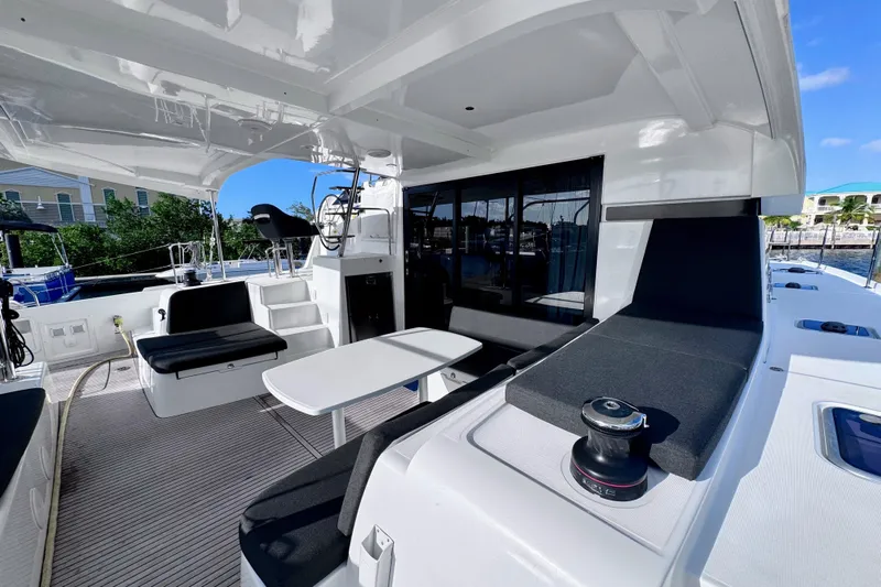  Yacht Photos Pics 2024 Lagoon 42 catamaran cockpit with seating, table, and helm station in marina setting.