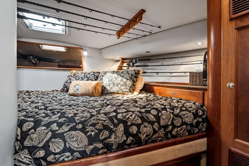 Lilli Ann Yacht Photos Pics Luxurious cabin interior of 2001 Rampage 38 Express with fishing rods and patterned bedding.