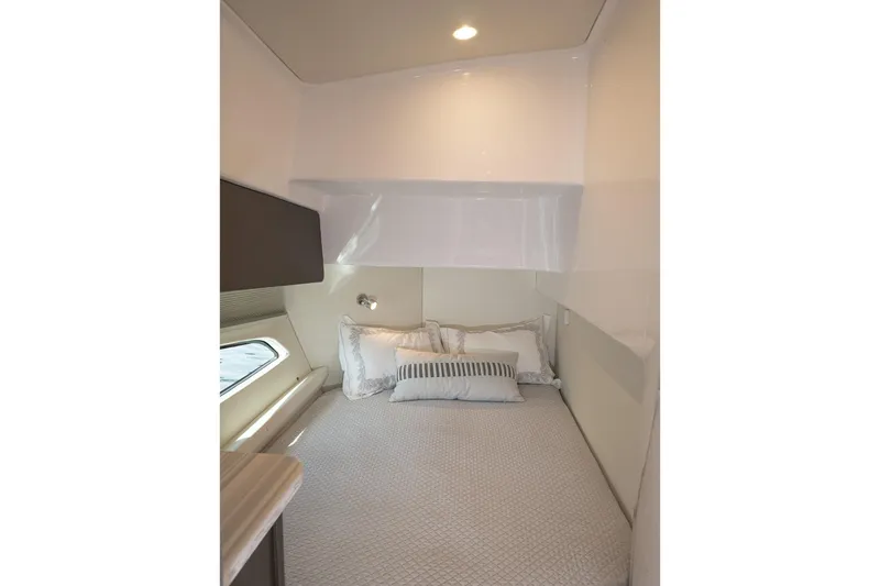 Garbonzo Yacht Photos Pics Cozy cabin interior of 2022 Intrepid 477 Evolution yacht with bed and window.