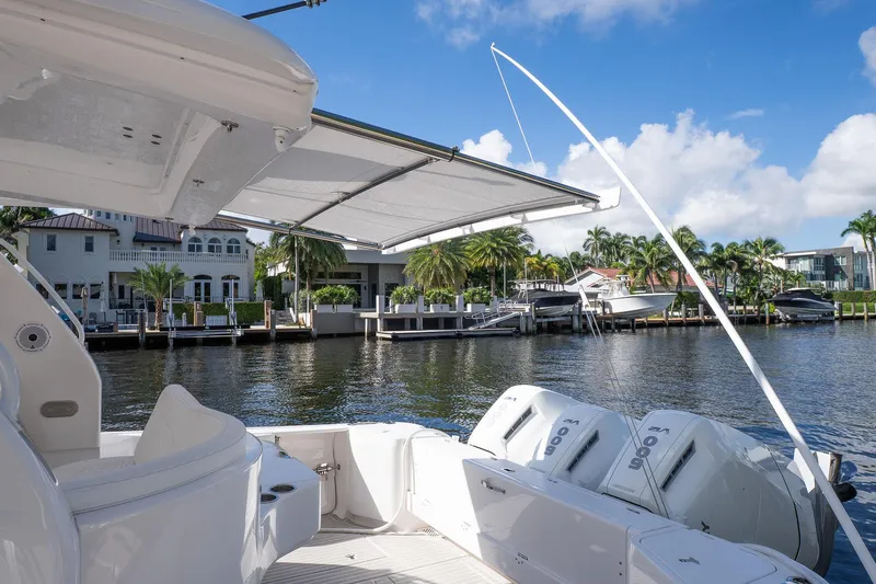 Garbonzo Yacht Photos Pics 2022 Intrepid 477 Evolution boat with canopy, docked by waterfront homes.