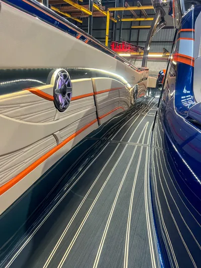 Thunder Struck Yacht Photos Pics 2024 MTI V42 boat with sleek design and vibrant orange accents in a showroom.