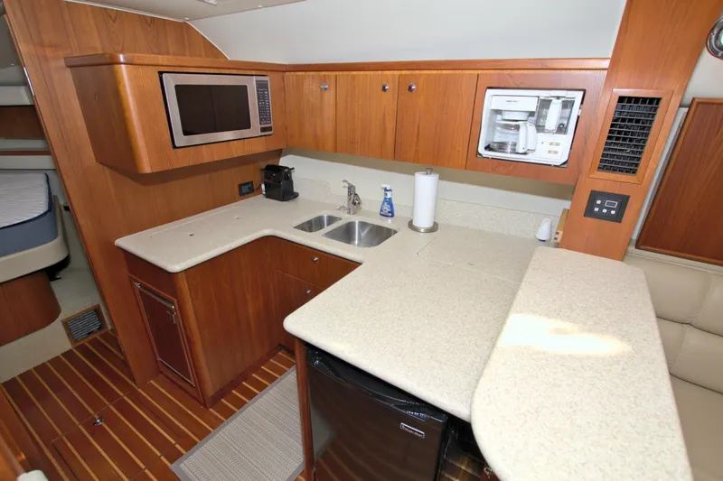 Ohana Yacht Photos Pics 2003 Tiara Yachts 4000 Express kitchen with microwave, sink, and wooden cabinetry.