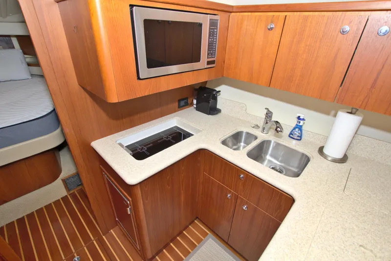Ohana Yacht Photos Pics 2003 Tiara Yachts 4000 Express kitchen with microwave, sink, and wooden cabinetry.