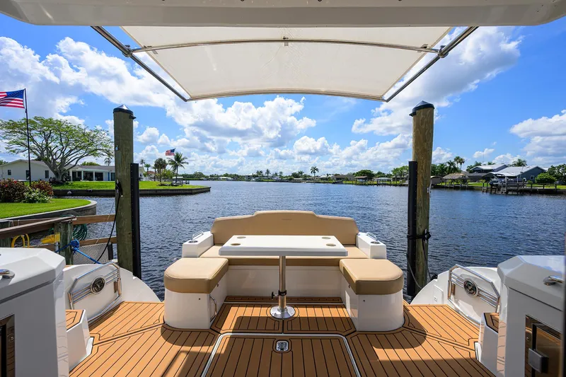 Ajac Cruiser Yacht Photos Pics 2015 Cruisers Cantius yacht deck with seating, overlooking serene waterfront and blue sky.