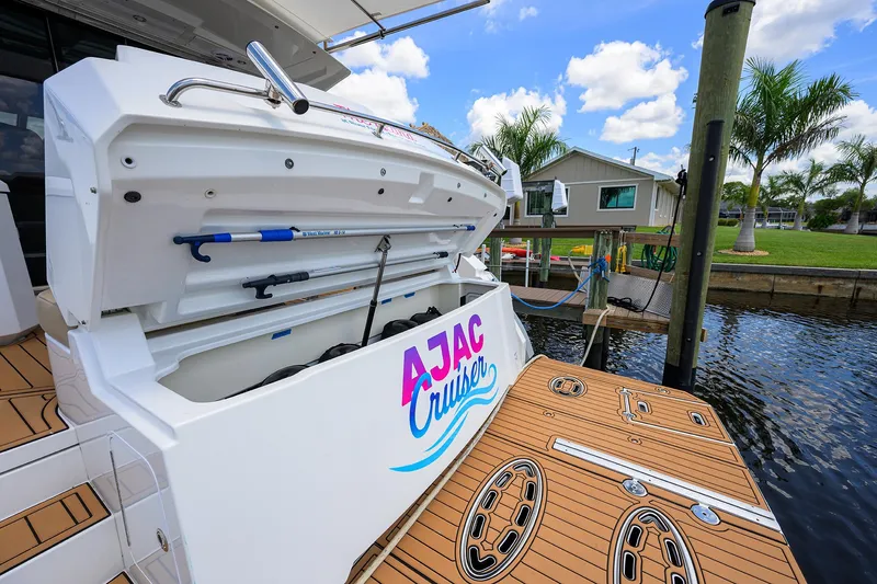 Ajac Cruiser Yacht Photos Pics 2015 Cruisers Cantius yacht with open storage, docked by palm trees under a blue sky.