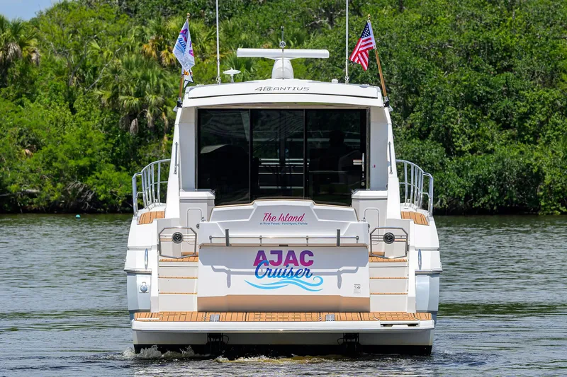 Ajac Cruiser Yacht Photos Pics 2015 Cruisers Cantius yacht on water, rear view with flags and lush greenery.