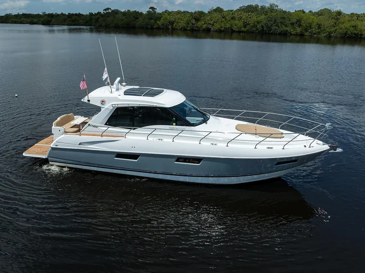 Ajac Cruiser Yacht Photos Pics 2015 Cruisers Cantius yacht cruising on calm water, surrounded by lush greenery.