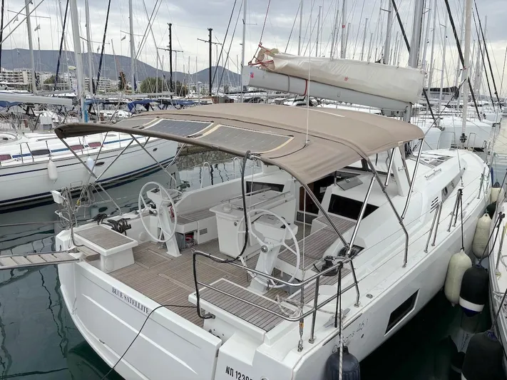 Blue Satellite Yacht Photos Pics 2019 Beneteau Oceanis 46.1 yacht docked in marina, featuring dual steering wheels and sunshade.