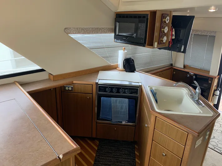 Yacht Photos Pics 2000 Bayliner 3988 yacht kitchen with stove, sink, and microwave in a compact layout.