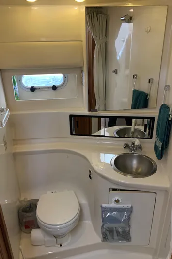  Yacht Photos Pics Bayliner 3988 2000 yacht bathroom with sink, toilet, mirror, and porthole window.