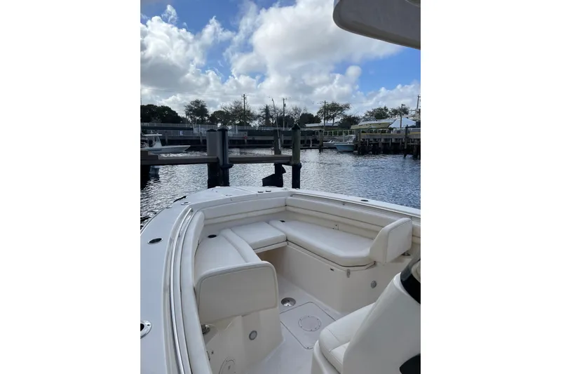  Yacht Photos Pics 2023 Grady-White Canyon 306 boat interior at dock, featuring white seating and calm waters.