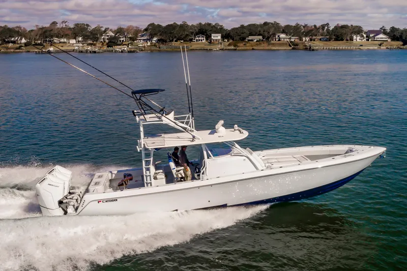 Fin Print Yacht Photos Pics 2023 Contender 44FA 44ST boat cruising on a calm lake near a residential shoreline.