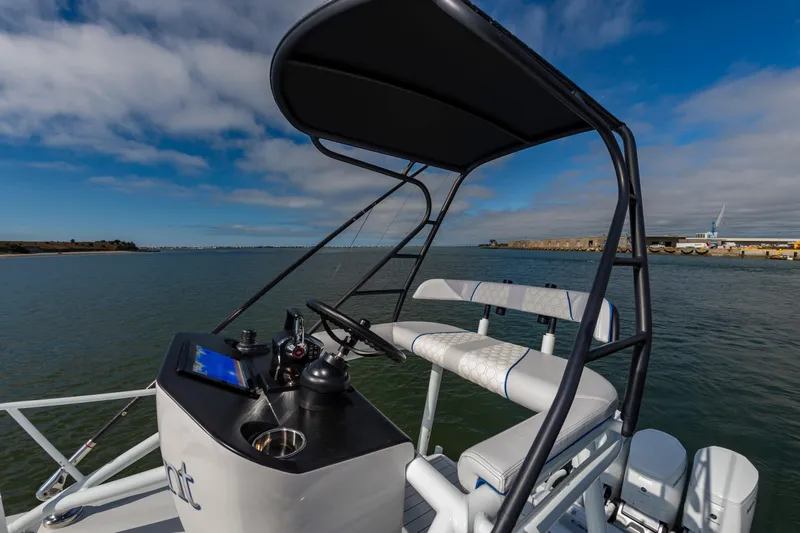 Fin Print Yacht Photos Pics 2023 Contender 44FA boat helm with seating, overlooking calm waters and a distant shoreline.