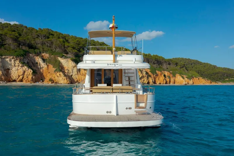  Yacht Photos Pics 2026 Sasga Yachts 55 cruising near scenic rocky coastline under clear blue sky.