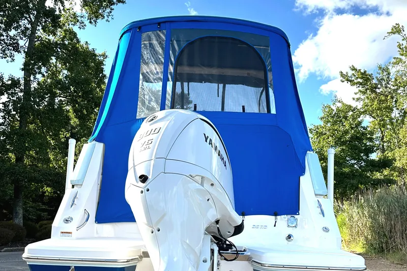  Yacht Photos Pics 2022 Regal 26XO boat with Yamaha outboard motor and blue canopy, surrounded by trees.
