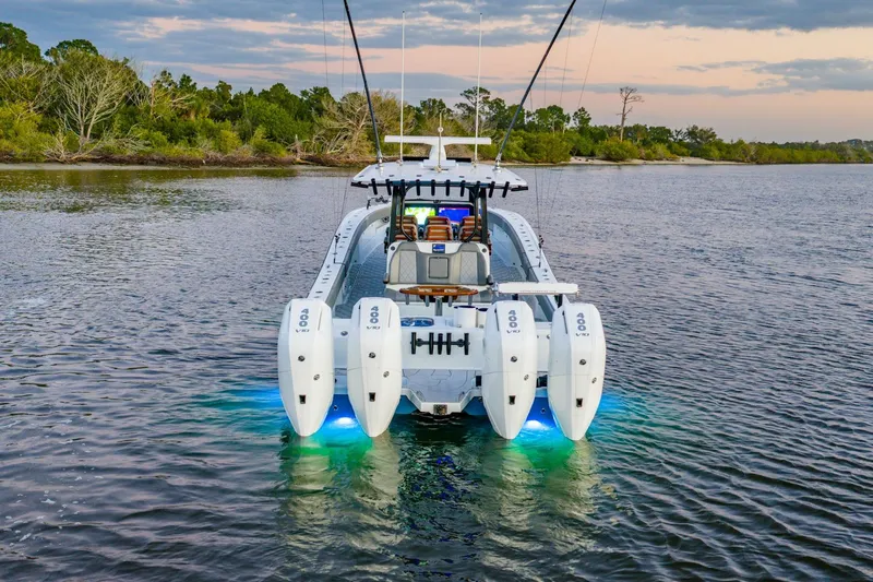  Yacht Photos Pics 2025 Freeman 43 boat with quad engines, illuminated on calm water at sunset.