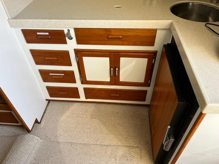  Yacht Photos Pics 1993 Radovich 34 boat kitchen with wooden cabinets, drawers, and a small fridge.